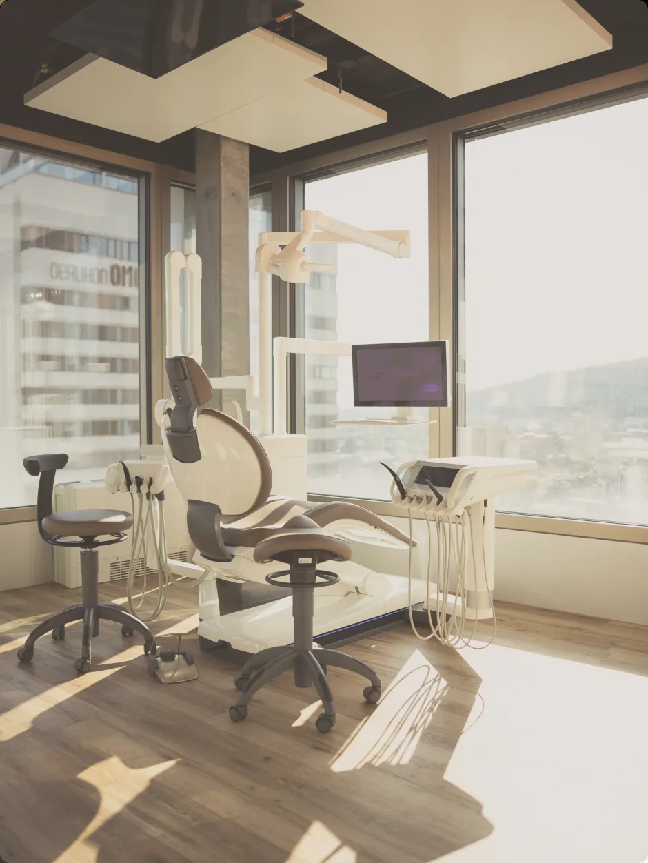 Ein moderner Behandlungsstuhl im Sonnenlicht in unseren schön eingerichteten Behandlungszimmern der Zahnarzt-Praxis CITYDENTAL Oerlikon im Franklinturm, der eine atmosphärische und entspannte Behandlungsumgebung schafft.