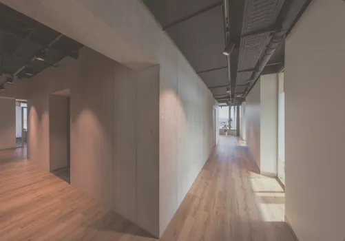 Architektonisch gestalteter Flur der Zahnarzt-Praxis CITYDENTAL Oerlikon im Franklinturm. Der moderne Gangbereich zeigt ein Zusammenspiel von warmem Holz und kühlem Beton, welches durch natürliches Licht eine entspannende Atmosphäre schafft.