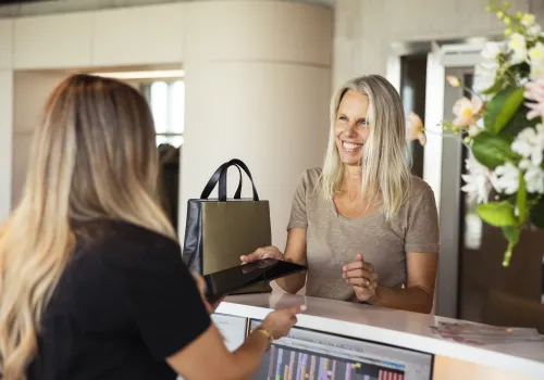 Rezeptionistin der Zahnarztpraxis CITYDENTAL Oerlikon in Zürich, im freundlichen Gespräch mit einer Patientin an der einladenden Praxisrezeption.