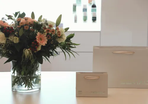 Fotoaufnahme eines Blumenstrausses und CITYDENTAL Papiertaschen auf dem Rezeptionstresen der Zahnarztpraxis CITYDENTAL Stettbach