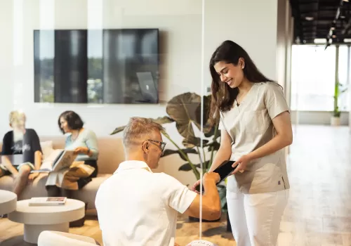 Dental Assistentin beim Zahnarzt Oerlikon hilft Patientin beim Ausfüllen des Anamnesebogens – Wartezimmer CITYDENTAL Zürich.