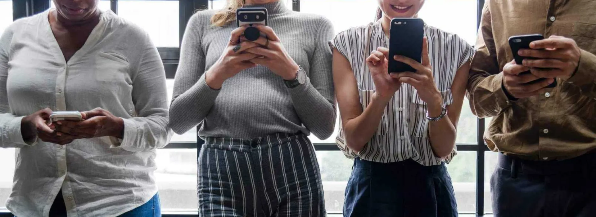Bildausschnitt vom Oberkörper von 4 Leuten, die am Handy etwas eintippen